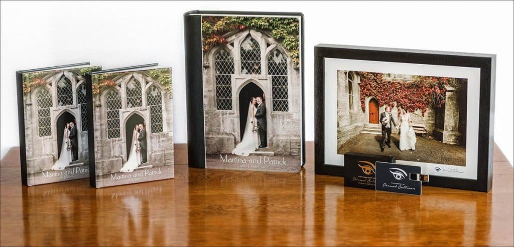 Three Wedding Albums and A Framed Wedding Photograph on a shiny wooden table.